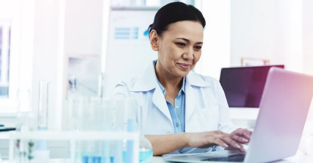 Female scientist working on laptop, conveying a Veeva Vault RIM Health Check